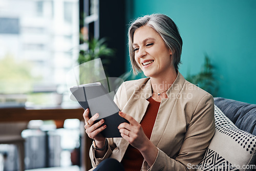 Image of The figures are looking great online. Cropped shot of an attractive mature businesswoman sitting alone and using a tablet in her home office.