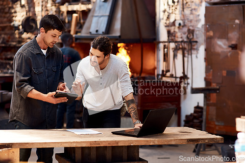 Image of Have a look at this. Cropped shot of two handsome young using their digital devices while working together inside their workshop.
