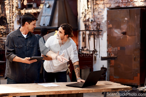 Image of We work better as a team. Cropped shot of two handsome young using their digital devices while working together inside their workshop.