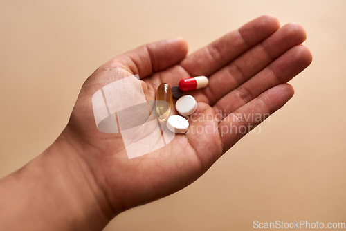 Image of Some illnesses require a cocktail of pills. Studio shot of an unrecognisable woman holding a handful of pills against a brown background.