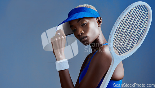 Image of You cant beat me even if you tried. Studio shot of a sporty young woman posing with a tennis racket against a blue background.