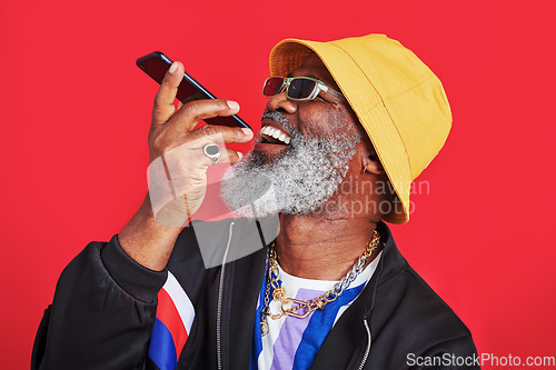 Image of Sending voice messages to make everyones day. Studio shot of a mature man holding his cellphone against a red background.