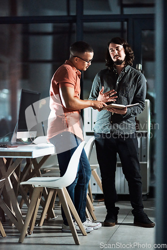 Image of Hes giving me some really cool ideas. Shot of two businessmen discussing in a notebook while working late.