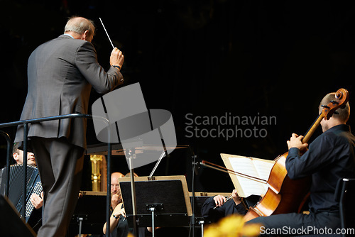 Image of Leading the orchestra in a symphony. Shot of a conductor and musicians during an orchestral concert.