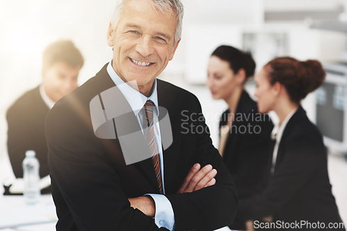 Image of Business is very good indeed. Portrait of a mature businessman with colleagues standing in the background.