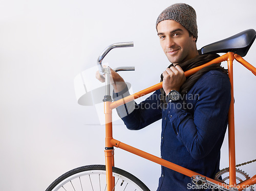 Image of Like my wheels. Cropped portrait of a trendy young man carrying his bicycle indoors.