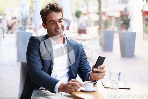 Image of Shes on the way....Shot of a young businessman reading a text while sitting at an outdoor cafe.