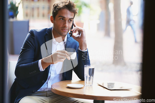 Image of Business even when on break. Shot of a young businessman enjoying a cup of coffee and talking on the phone.