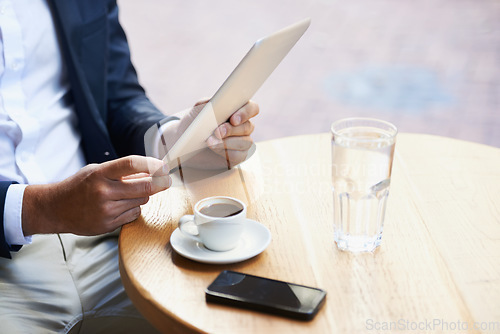 Image of Online from anywhere he goes. Cropped view of a businessman using his digital tablet in a cafe while he waits.