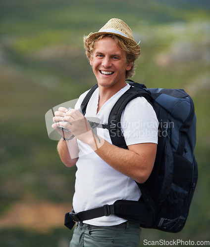 Image of The view from up here is sublime. Shot of a young man with binoculars hiking outdoors.