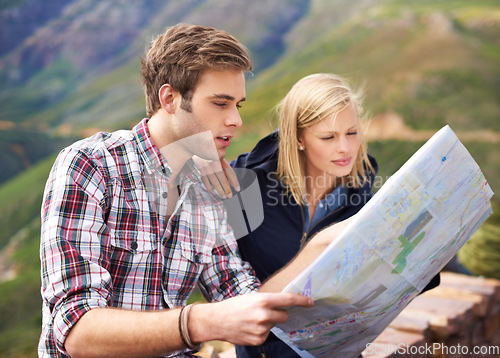 Image of Which way should we go. A shot of a young couple looking at a map on their road trip.