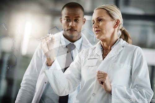 Image of Working out the perfect formula. Cropped shot of two scientists writing down formulas on a glass wipe board while doing research in their lab.