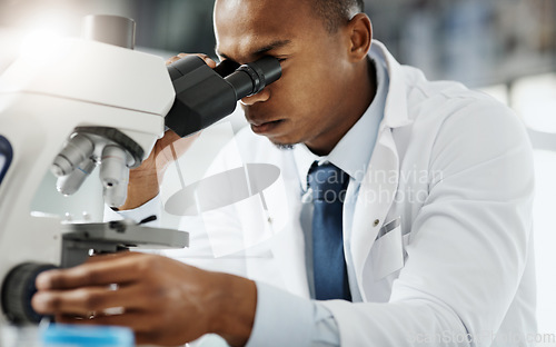 Image of Looking closer...Cropped portrait of a handsome young male scientist using a microscope while doing research in his lab.