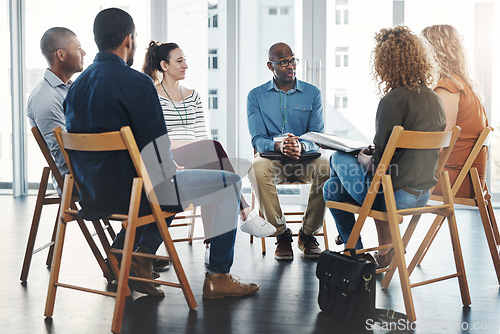 Image of Gathered round for a meeting. Shot of a group of diverse creative employees having a meeting inside.