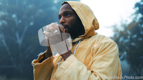 Image of Coffee, morning and black man hiking in the forest with a blurred background of cold, winter weather. Thinking, raincoat and face of a young male hiker in the woods or nature to explore for adventure