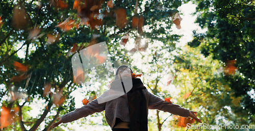 Image of Woman, autumn and throwing leaves outdoor in a park with trees, freedom and fun in nature. Happy and excited person in warm clothes while playful on an adventure, travel or holiday in fall season