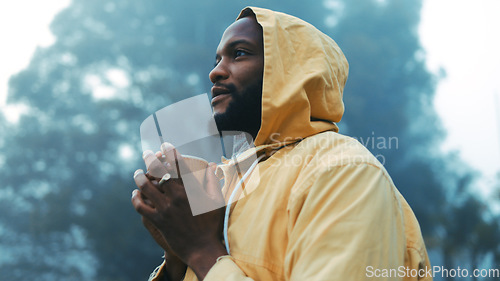 Image of Coffee, morning and black man hiking in the forest with a blurred background of cold, winter weather. Thinking, raincoat and face of a young male hiker in the woods or nature to explore for adventure