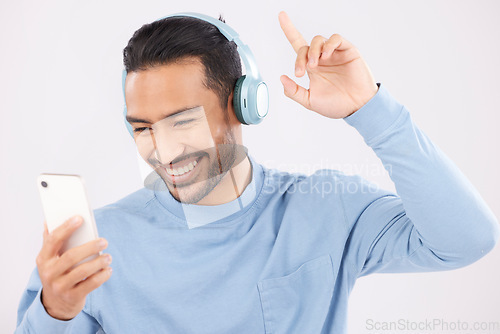 Image of Headphones, phone and man dancing in a studio with music, album or playlist with technology. Happy, smile and Indian young male person doing a dance to song or radio isolated by a white background.