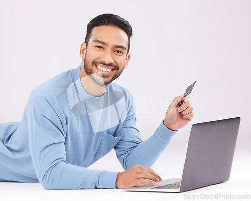 Image of Laptop, credit card and asian man portrait on studio floor for ecommerce, sale or cashback on grey background. Online shopping, face and Japanese guy customer smile for loan, payment or sign up promo