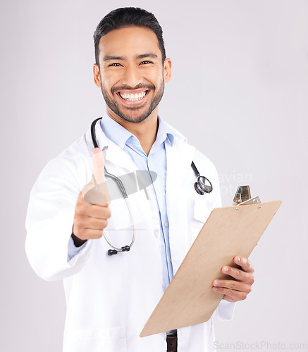 Image of Happy asian man, doctor and portrait with thumbs up for healthcare approval against a grey studio background. Male person or medical expert smile with clipboard, like emoji or yes sign for success