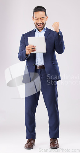 Image of Happy businessman, tablet and fist pump for winning, promotion or bonus against a grey studio background. Excited asian man in celebration on technology for good news, lottery prize or sale discount