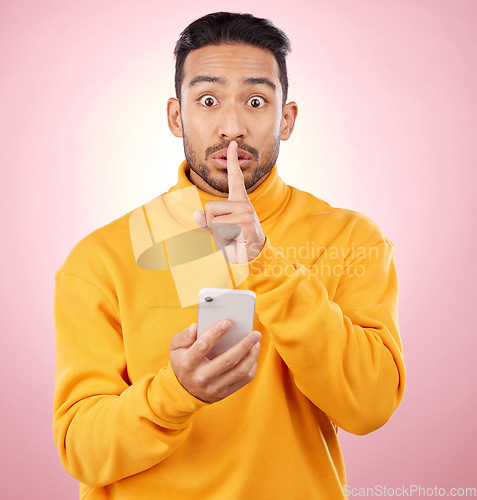 Image of Man, phone and studio with finger, silence and sign language for secret promotion by pink background. Gen z guy, student or fashion model with smartphone, hand and lips for portrait, deal and sale