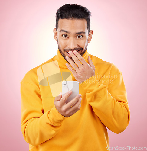 Image of Phone, shock and portrait of a man in studio with a secret, gossip or fake news on social media. Male asian model with hand on mouth and smartphone for wow, surprise or chat on a pink background