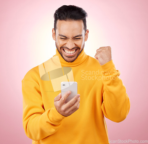 Image of Winner, man and phone for success, yes and celebration of online news, social media or gaming results. Excited, mobile games and person reading notification or website bonus on pink studio background