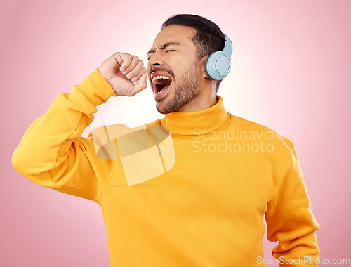 Image of Asian man, headphones and listening to music for karaoke or singing against a pink studio background. Happy male person enjoying online audio streaming, sound track or songs with headset on mockup