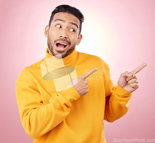 Image of Pointing finger, advertising and a man in studio with a wow announcement, promotion or decision. Face of male asian model with hands for marketing sale, news or presentation on a pink background