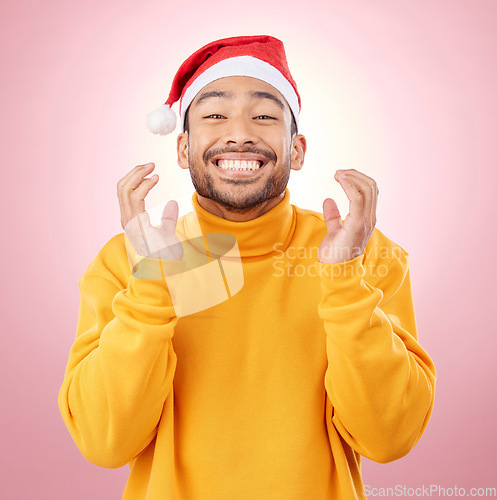 Image of Portrait, excited and happy man with Christmas hat, fun and festive for holiday on pink background. Happiness, celebration and model with smile, santa cap and winter vacation fashion jersey in studio