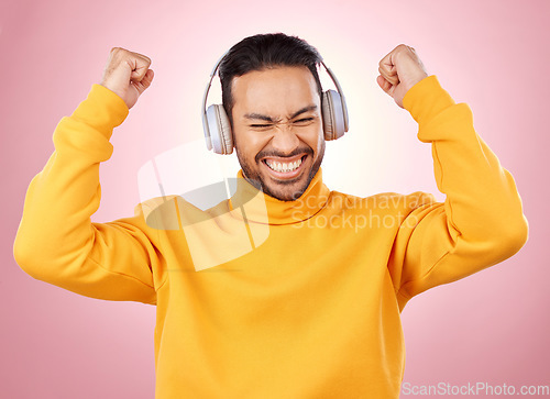 Image of Music, headphones and man or winner success, yes and celebration for podcast, radio news and bonus. Motivation, power and happy person dance, listening to audio and excited on studio pink background