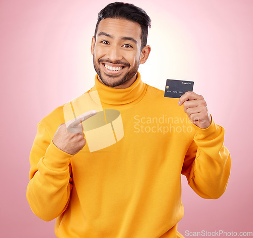 Image of Man, pointing and credit card with finance, payment and loan, budget and fashion sale on studio pink background. Portrait, banking and happy asian person or gen z with retail transaction or shopping