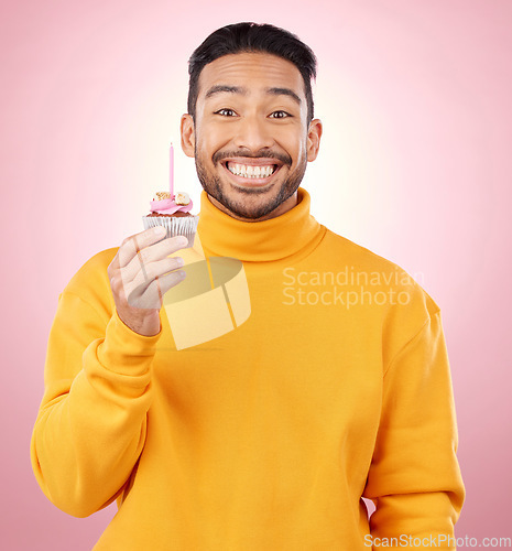 Image of Man, portrait and cupcake for birthday, celebration and winner, success or achievement on pink background. Excited, happy and young asian person with candle and cake for winning competition in studio