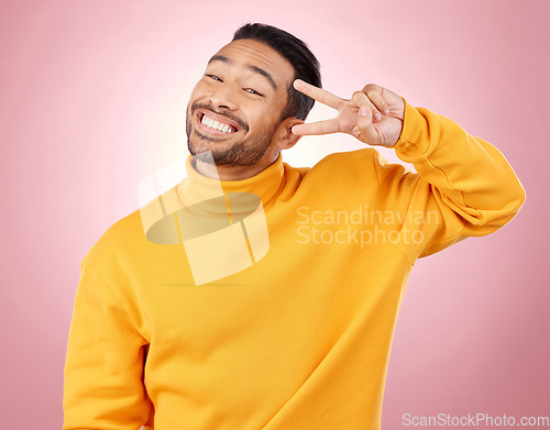 Image of Happy, peace sign and portrait of man in studio for support, kindness and emoji. Smile, happiness and thank you with face of person on pink background for mindfulness, vote and v hand gesture