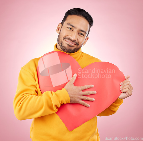 Image of Heart, poster and love with portrait of man in studio for romance, date and valentines day. Kindness, support and hope with person and sign on pink background for wellness, peace and creative mockup