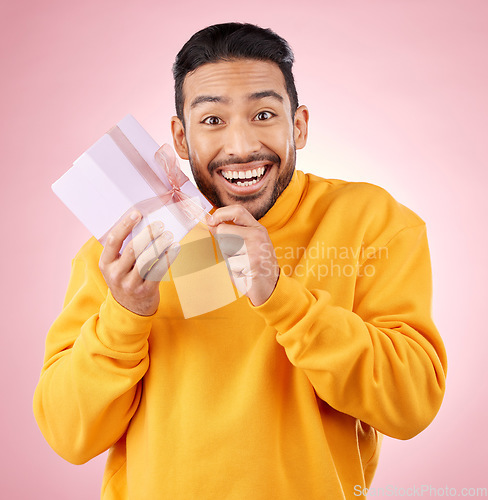 Image of Young man, gift box and studio portrait with excited smile, ribbon and open for celebration by pink background. Asian gen z student, present or prize for giveaway, competition or package for party