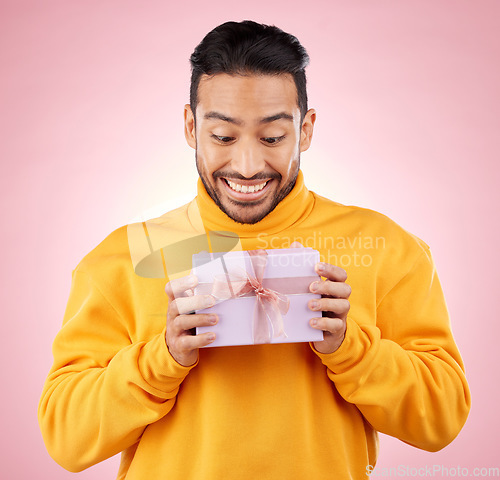 Image of Man, winner and excited for gift box, prize and giveaway celebration or birthday surprise on pink background. Happy person with present, package and retail shopping or competition success in studio