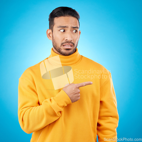 Image of Wtf, surprise and asian man hand pointing in studio for menu, questions and how to steps on blue background. Omg, doubt and male face with finger show feedback, schedule or presentation with anxiety