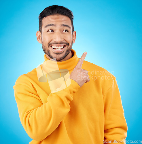 Image of Asian man, smile and hand pointing to studio for news, deal and discount or how to guide on blue background. Happy, choice and male show timeline, checklist or direction, coming soon or sign up info