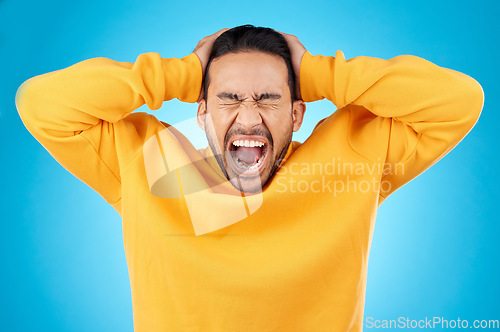 Image of Angry, man and face with screaming in studio with burnout, anxiety and stress. Isolated, blue background and frustrated by problem with male person yelling and mental health from mistake and issue