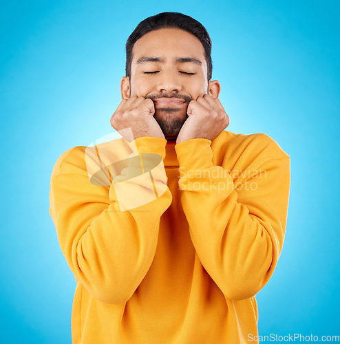 Image of Man, shy and touching cheeks in studio isolated on a blue background. Peace, calm and person in love, relax for zen and meditation, content and satisfied with eyes closed, hands on face and wellness