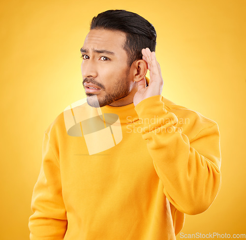 Image of Whisper, gossip and asian man with hand on ear in studio for speak up body language on yellow background. Secret, listen and male person with hush, news or confidential coming soon promo announcement