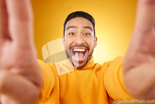 Image of Funny, portrait and selfie of excited man in studio isolated on a yellow background. Face, smile and Asian person taking profile picture for happy memory, laughing and photography on social media