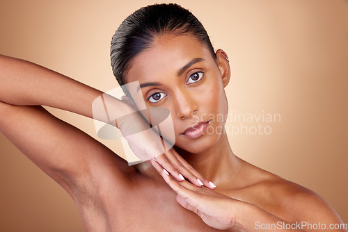 Image of Beauty, portrait and indian girl for skincare with hands in brown studio background. Dermatology, face and spa treatment with self care or natural cosmetics in mock up for luxury facial or wellness.