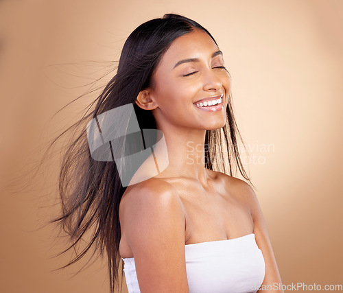 Image of Salon, hairstyle and indian woman with beauty or wind in brown studio background. Happy, girl and haircare with eyes closed or keratin treatment for shine or volume and natural cosmetics with glow.