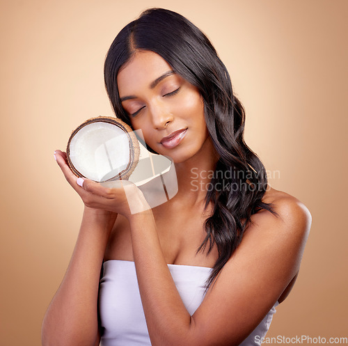 Image of Coconut, fruit and woman with natural beauty, skincare or vegan product in cosmetics for healthy skin glow, shine or benefits. Tropical fruits, Indian model and organic oil for cosmetic cream