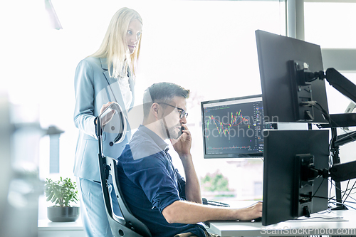 Image of Stock broker business team trading online watching charts and data analyses on multiple computer screens in modern corporate work station office.