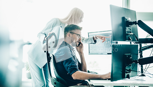 Image of Stock broker business team trading online watching charts and data analyses on multiple computer screens in modern corporate work station office.