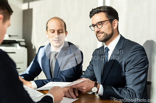 Image of Group of confident successful business people reviewing and signing a contract to seal the deal at business meeting in modern corporate office.